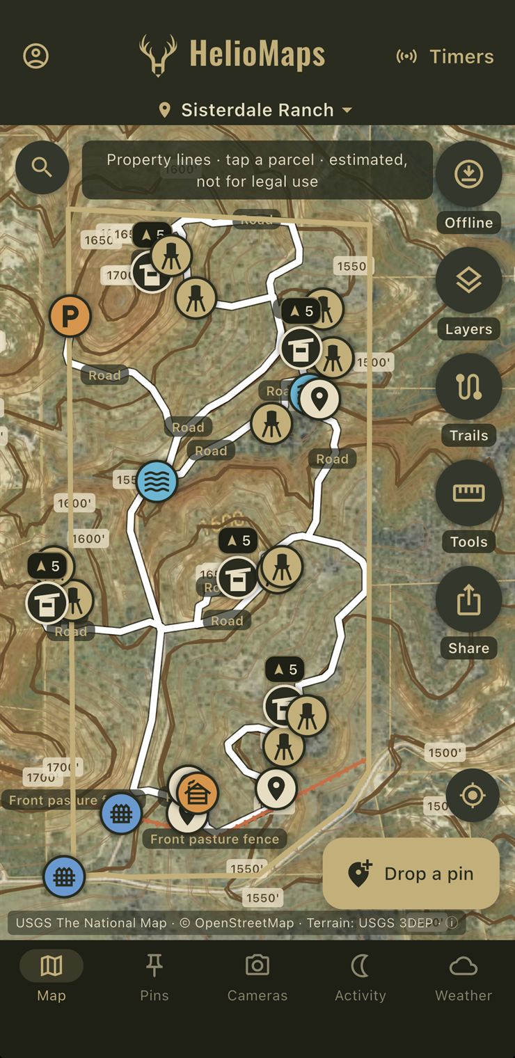 HelioMaps app showing Sisterdale Ranch with property lines, terrain contours, roads and trails, and feeder, blind, water, gate and parking pins on satellite imagery